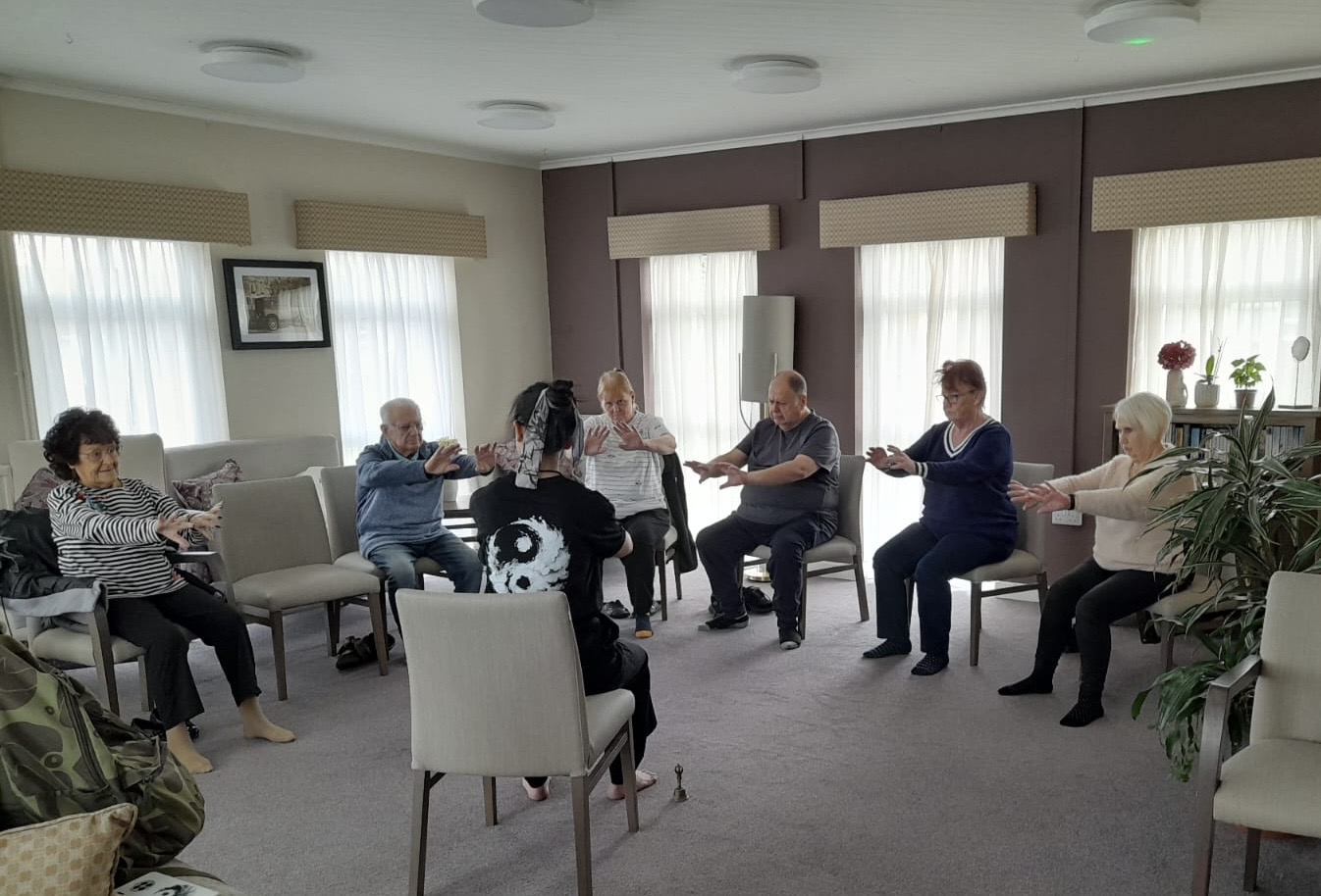 A seated community group practising Tai Chi together
