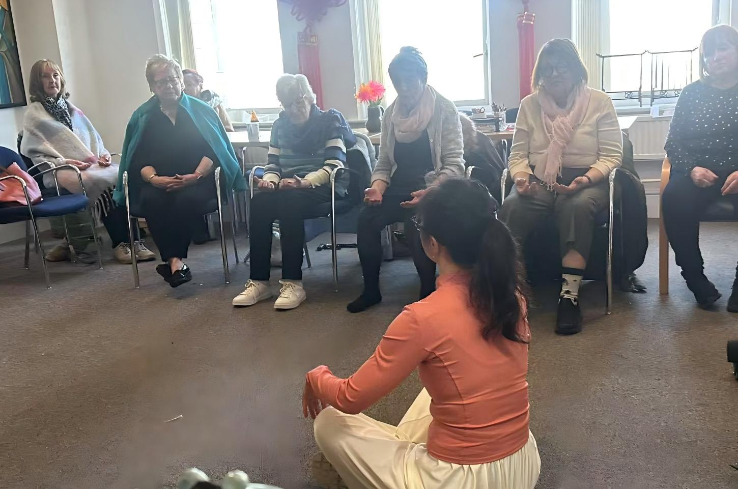 Dr Jar guiding women through a calm seated Tai Chi session